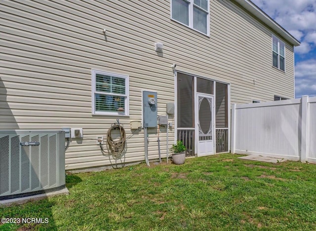 entrance to property featuring cooling unit and a lawn