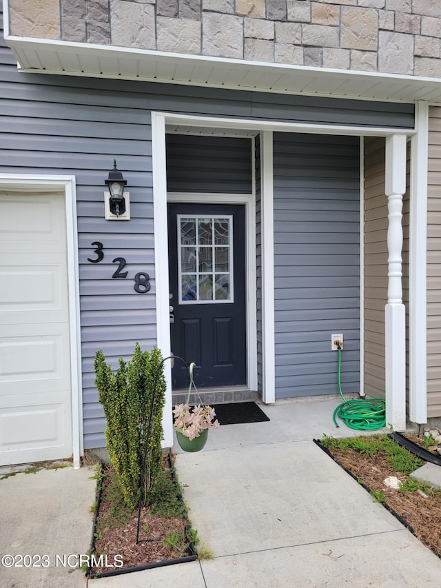 doorway to property featuring a porch and a garage