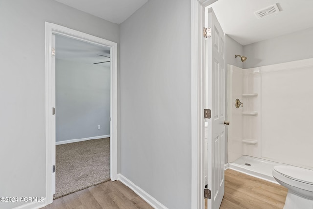 bathroom featuring toilet, walk in shower, and wood-type flooring