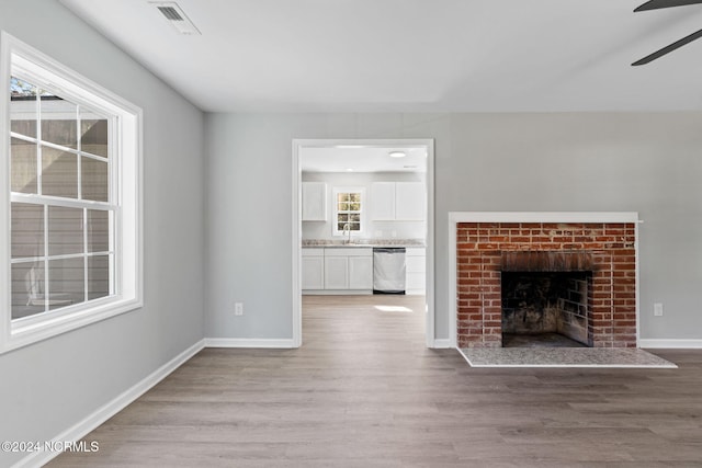 unfurnished living room featuring light hardwood / wood-style flooring, a fireplace, and ceiling fan