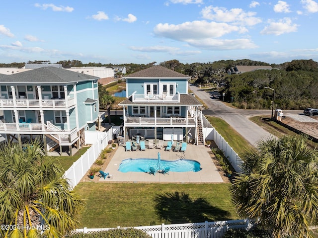 rear view of house featuring a fenced in pool, a yard, a patio, a balcony, and a fenced backyard