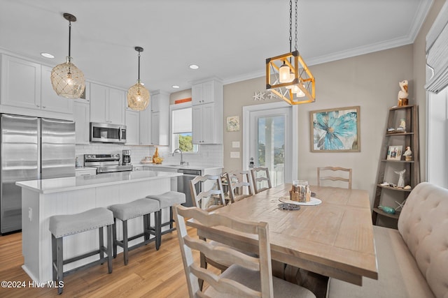 dining space with recessed lighting, crown molding, and light wood-style flooring