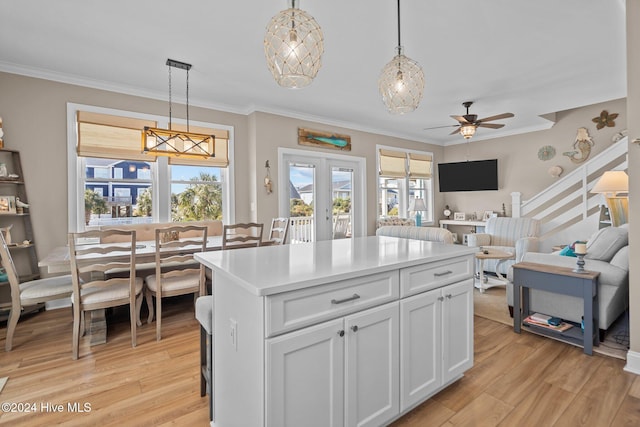 kitchen with light countertops, hanging light fixtures, open floor plan, white cabinets, and a kitchen island