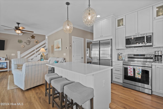 kitchen with white cabinetry, open floor plan, light countertops, appliances with stainless steel finishes, and glass insert cabinets