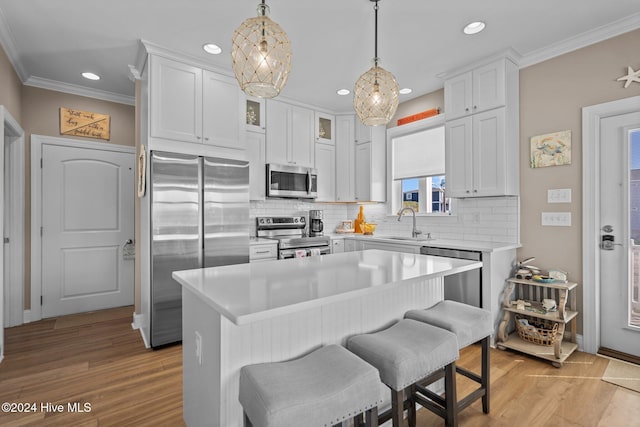 kitchen featuring white cabinetry, stainless steel appliances, light countertops, and a center island