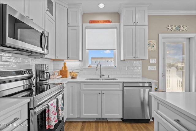 kitchen featuring stainless steel appliances, light countertops, backsplash, white cabinetry, and a sink