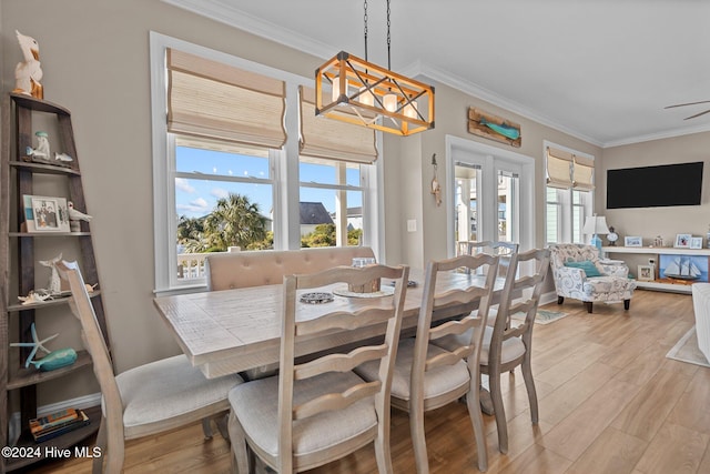 dining space with light wood-style floors, ornamental molding, and an inviting chandelier