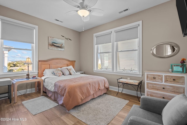 bedroom with light wood finished floors, a ceiling fan, visible vents, and baseboards