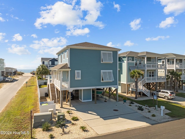 view of front of house with a carport, stairway, concrete driveway, and a residential view