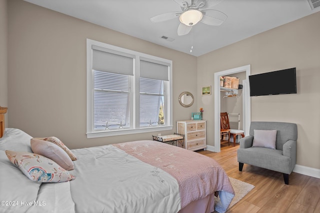 bedroom featuring baseboards, visible vents, ceiling fan, a walk in closet, and light wood-style floors