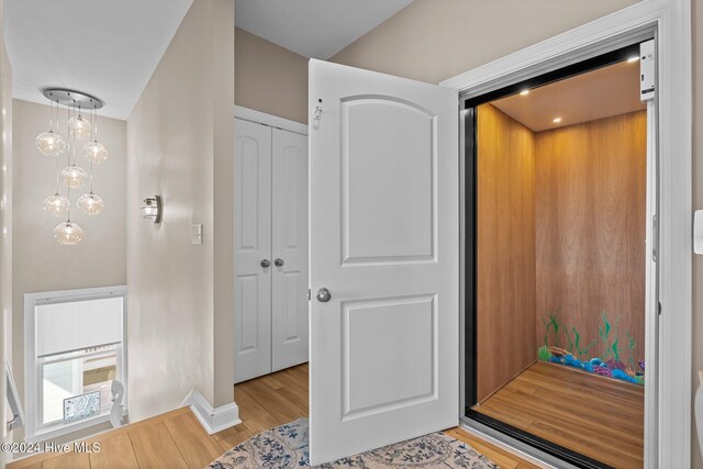 hall featuring baseboards, light wood-style flooring, and elevator