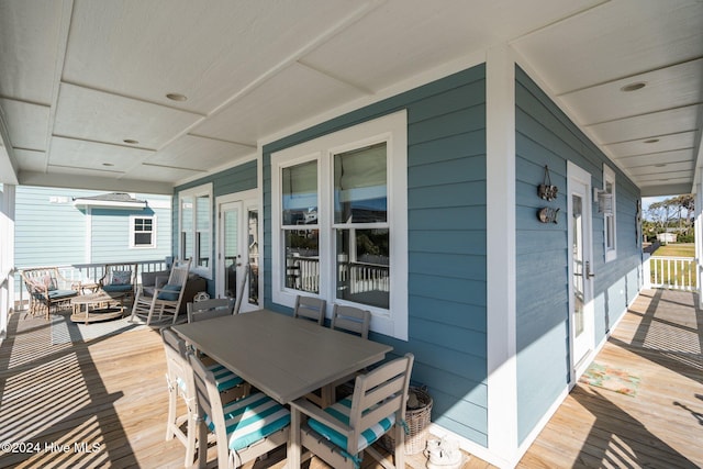 wooden deck with a porch and outdoor dining area