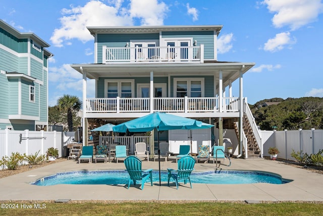 rear view of property featuring fence private yard, a balcony, stairs, a fenced in pool, and a patio area