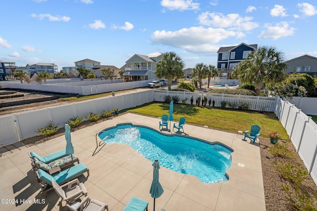 view of swimming pool featuring a fenced in pool, a patio, a fenced backyard, a residential view, and a yard