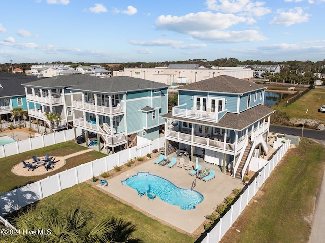 back of house featuring a fenced in pool, a patio, a balcony, a fenced backyard, and a residential view