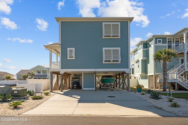 coastal inspired home with stairs, a carport, concrete driveway, and a residential view