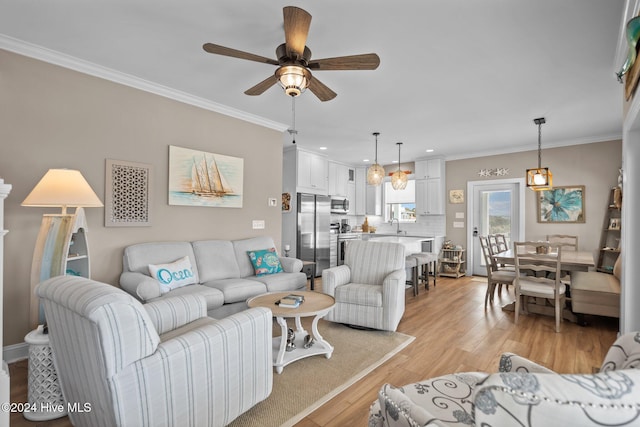 living area with light wood-type flooring, crown molding, and ceiling fan