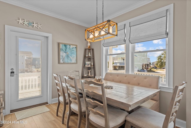 dining area with light wood-type flooring, an inviting chandelier, baseboards, and ornamental molding