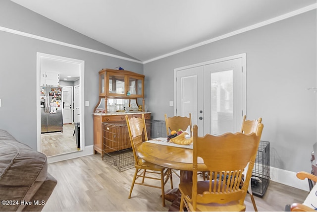 dining space featuring lofted ceiling, light wood-type flooring, and crown molding