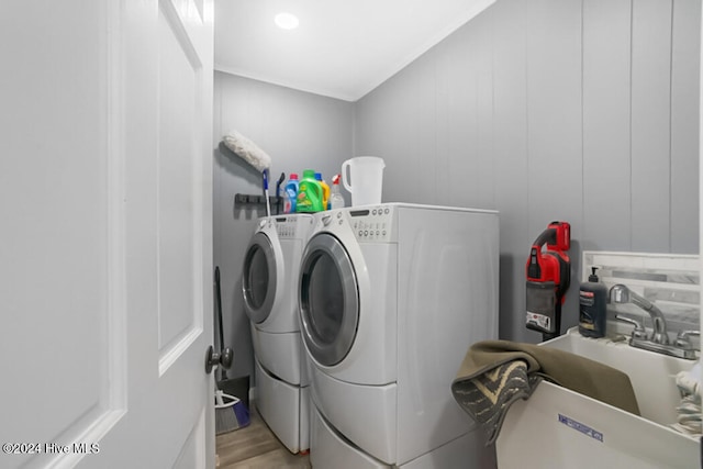 clothes washing area featuring sink, independent washer and dryer, and light wood-type flooring