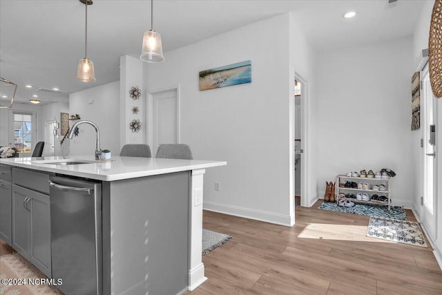 kitchen featuring a kitchen island with sink, stainless steel dishwasher, gray cabinetry, light hardwood / wood-style floors, and sink