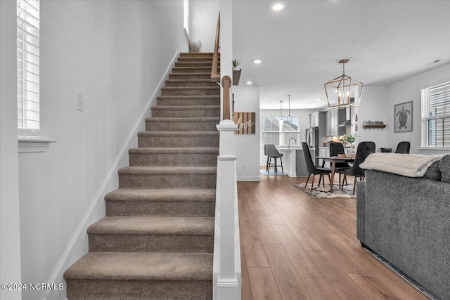 staircase with sink, an inviting chandelier, and hardwood / wood-style floors