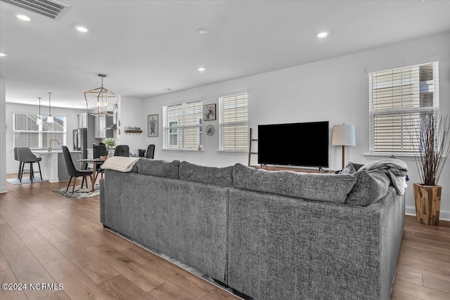 living room featuring a notable chandelier, sink, and wood-type flooring