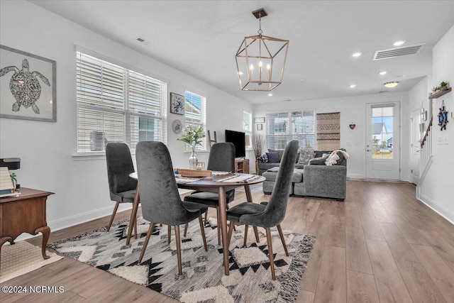 dining area featuring light hardwood / wood-style flooring, a notable chandelier, and plenty of natural light