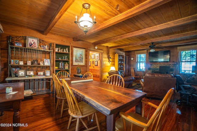 dining area featuring beam ceiling, a fireplace, wood-type flooring, and a healthy amount of sunlight