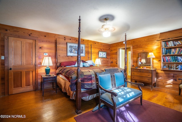 bedroom featuring wood walls, dark hardwood / wood-style floors, and ceiling fan