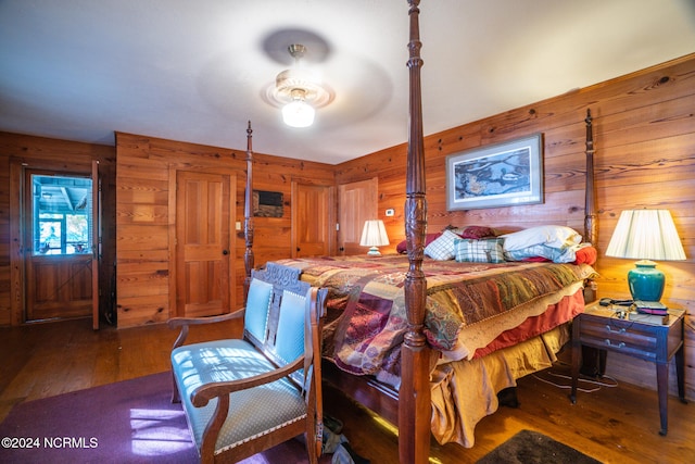 bedroom featuring wooden walls, wood-type flooring, and ceiling fan