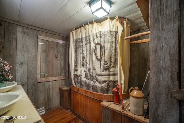 bathroom featuring vanity, wood walls, and hardwood / wood-style flooring