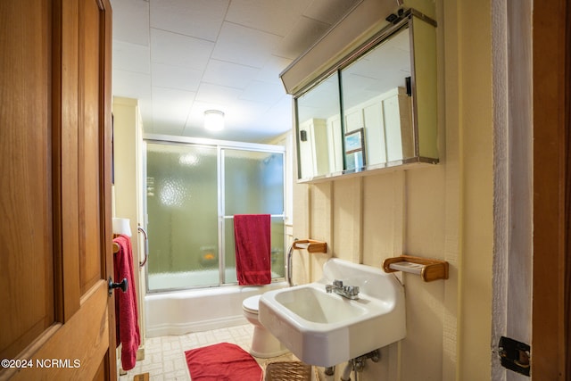 full bathroom featuring sink, toilet, and shower / bath combination with glass door