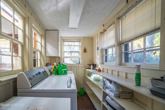 laundry room featuring wood walls, a textured ceiling, and washer and clothes dryer