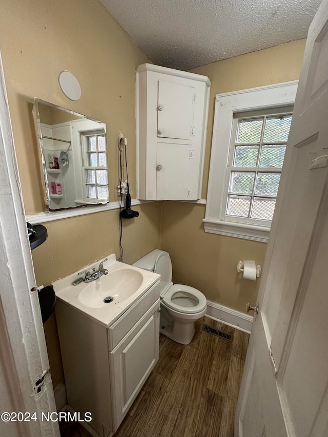 bathroom featuring toilet, a textured ceiling, hardwood / wood-style flooring, and vanity