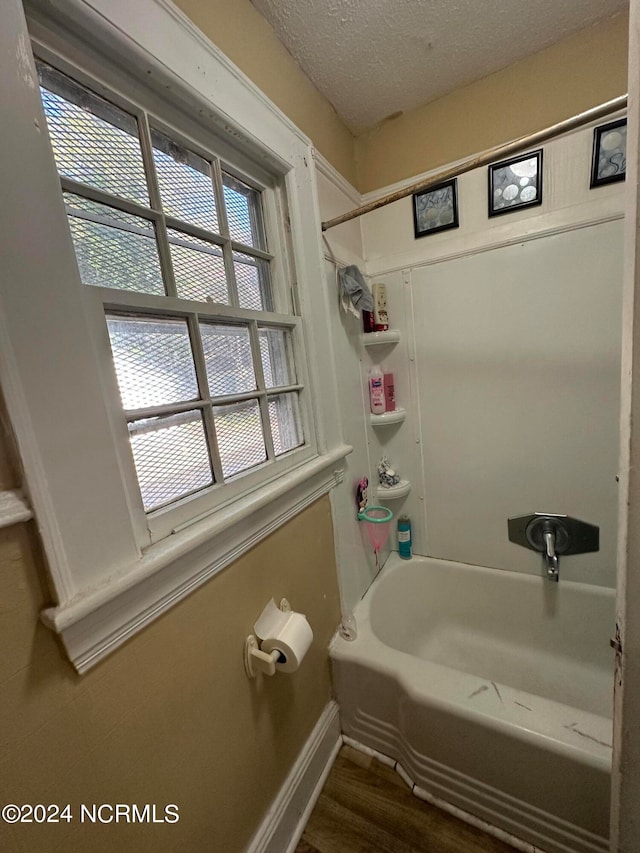 bathroom featuring a textured ceiling, a wealth of natural light, tub / shower combination, and hardwood / wood-style floors