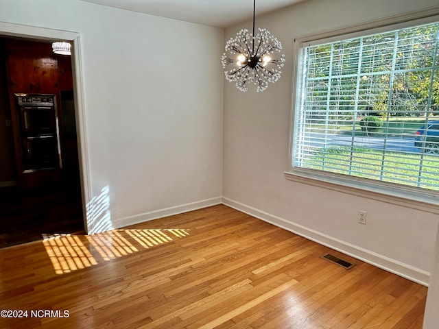 unfurnished dining area with light hardwood / wood-style floors, a notable chandelier, and plenty of natural light