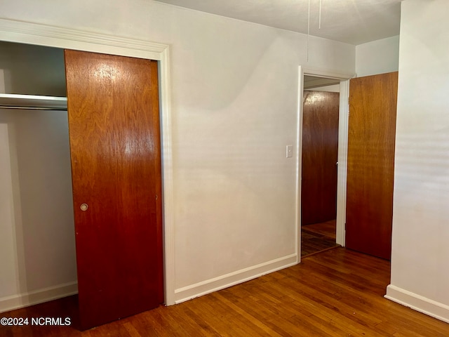 unfurnished bedroom featuring a closet and dark wood-type flooring