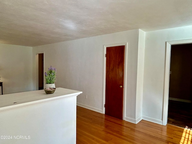 corridor featuring a textured ceiling and hardwood / wood-style floors