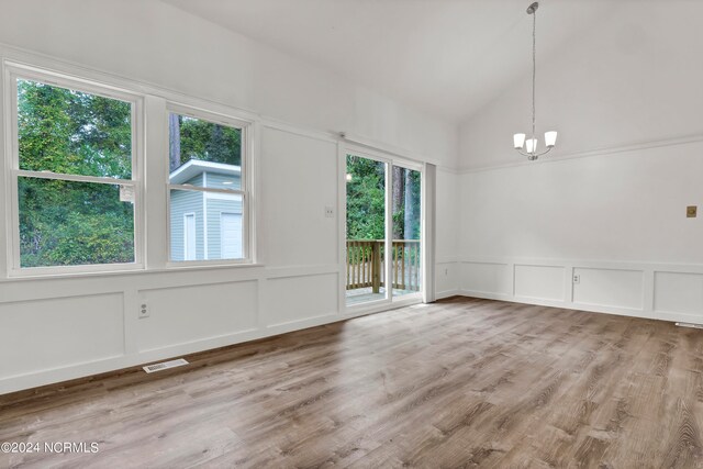 spare room with an inviting chandelier, hardwood / wood-style flooring, and vaulted ceiling