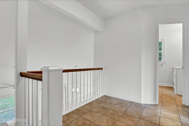 hall featuring beam ceiling and light tile patterned floors