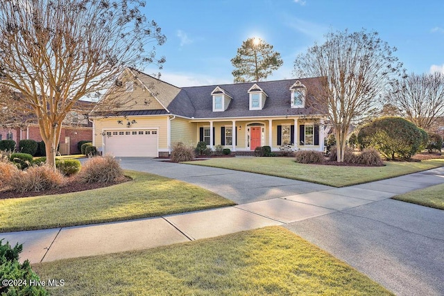 cape cod house with a front lawn, covered porch, and a garage