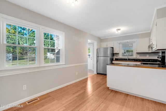 kitchen with appliances with stainless steel finishes, sink, kitchen peninsula, light hardwood / wood-style floors, and white cabinets