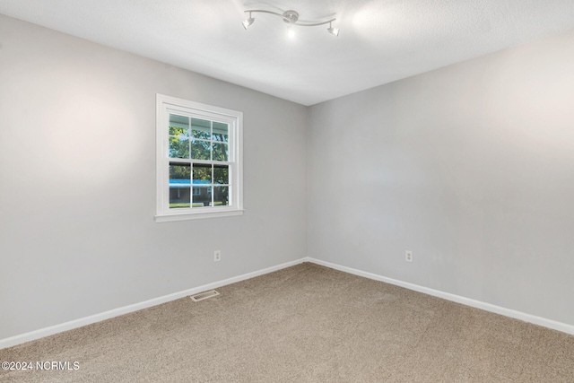 spare room featuring a textured ceiling and carpet