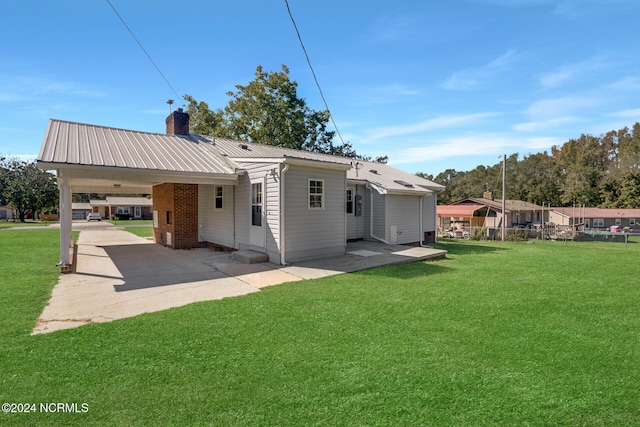 rear view of house featuring a patio, a lawn, and a carport