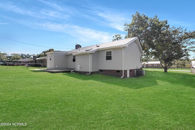 rear view of property with central air condition unit and a lawn