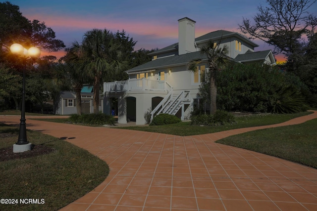 back house at dusk with a yard and a patio area