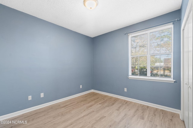 empty room featuring light hardwood / wood-style flooring, a textured ceiling, and a healthy amount of sunlight