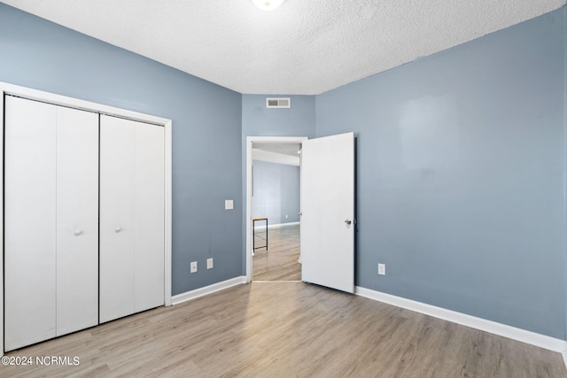 unfurnished bedroom with a closet, a textured ceiling, and light hardwood / wood-style floors