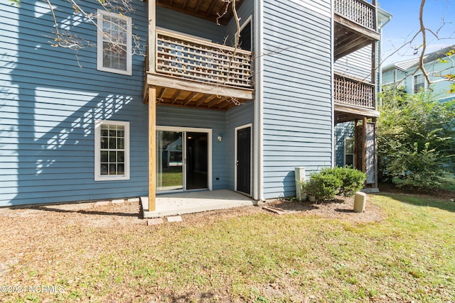 rear view of house featuring a patio area, a lawn, and a balcony